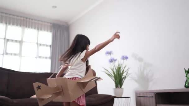 Девушка играет с картонной игрушкой самолета дома — стоковое видео