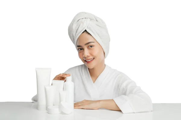 Beautiful girl model with towel on her head sitting with various skin care products on table — Stock Photo, Image