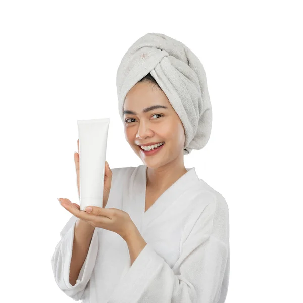 Attractive woman in towel with presenting hand presenting white tube bottle — Stock Photo, Image