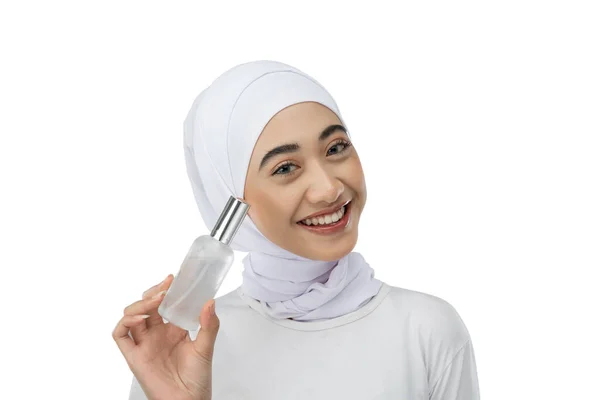 Excited asian hijab girl with perfect skin holding a bottle of facial care serum — Fotografia de Stock