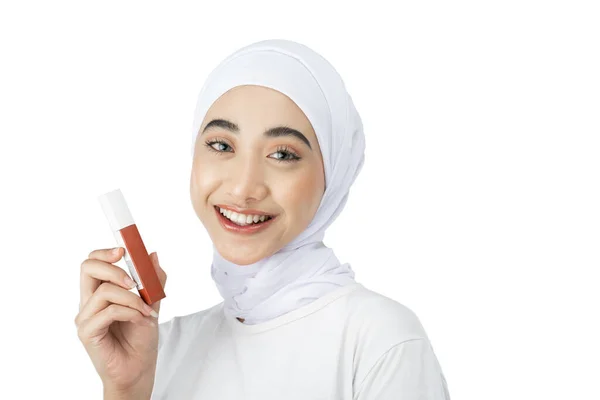 Beautiful muslim girl in hijab looking at camera while holding lipstick bottle — Stockfoto