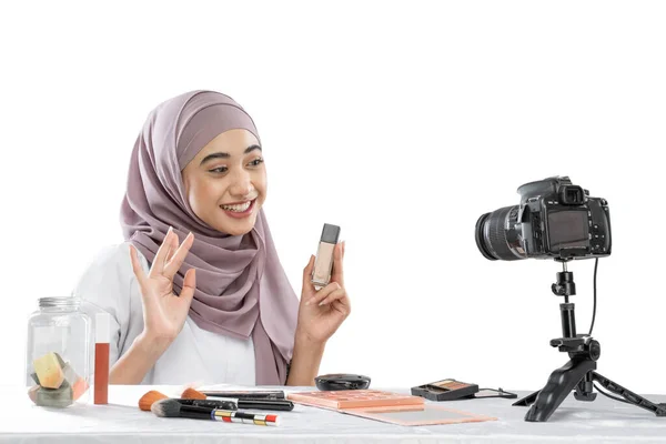 Beauty blogger in hijab holding a bottle of lipstick recording video with camera — Stock Photo, Image