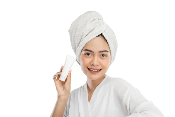 Smiling beautiful girl with towel on head holding tube bottle — Stock fotografie