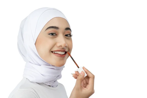 Smiling asian muslim women wearing hijab using lipstick with copyspace — Foto Stock