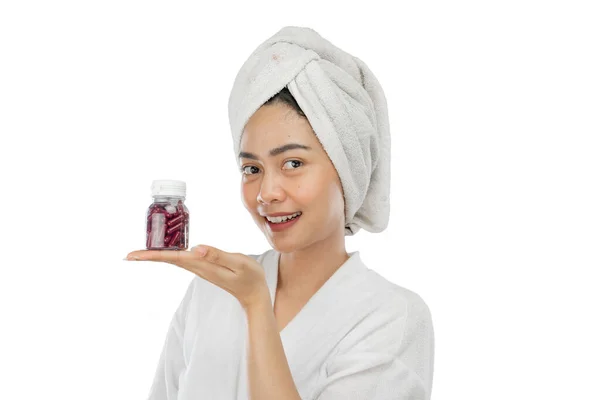 Atrakcyjna kobieta z ręcznikiem z gestem ręki prezentujący butelkę witamin — Zdjęcie stockowe