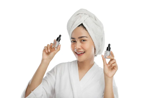 Beautiful girl with towel on head holding bottle of serum skin care products — Stockfoto