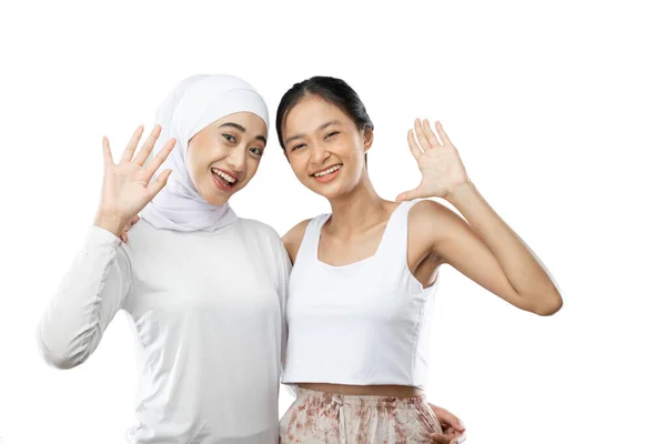 Smiling hijab girl and young girl smiling with waving hands to the camera —  Fotos de Stock