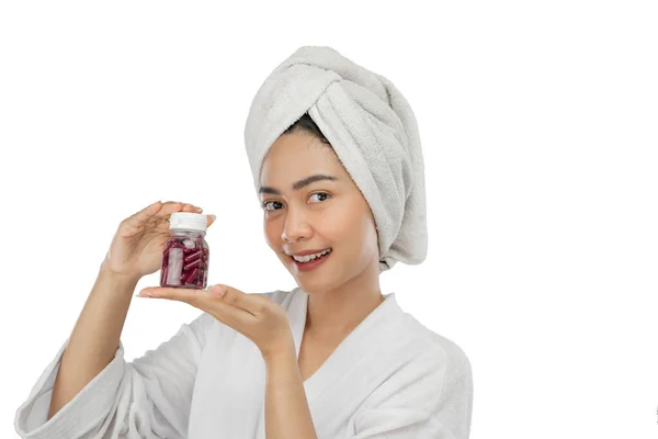 Piękna dziewczyna uśmiecha się ręcznikiem z gestem dwóch rąk prezentując butelkę witamin — Zdjęcie stockowe