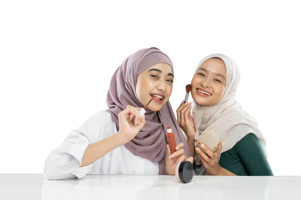Two beauty veiled girl holding brush and applying lipstick when making video — Stok fotoğraf