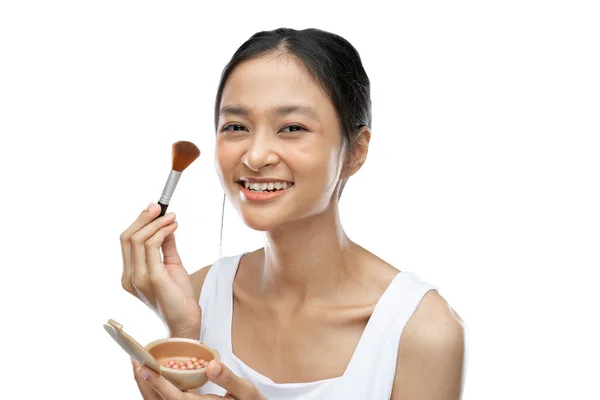 Smiling asian woman wearing underdress applying make up with brush — Stock fotografie