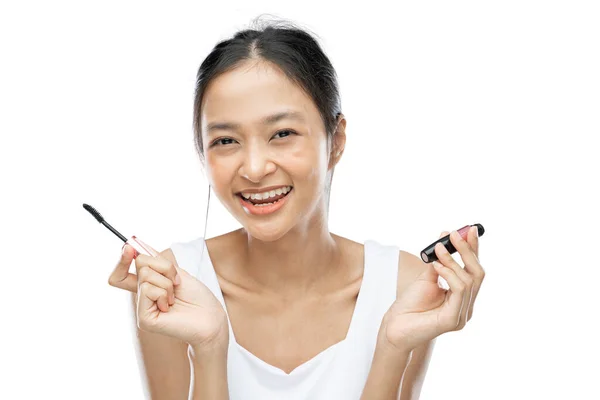 Smiling asian woman wearing white underdress holding mascara — Fotografia de Stock