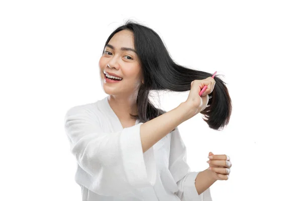 Beautiful woman wearing a towel combing beautiful long hair with a comb — Stockfoto