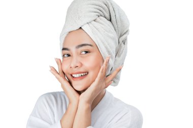asian girl with bath towel on head with both hands pose gently holding cheek with copy space