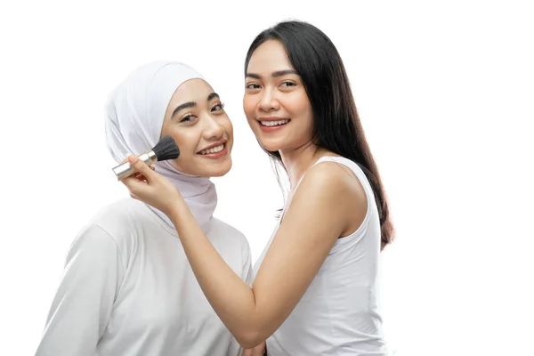 Beautiful woman makeup artist applying cheek with brush of young asian muslim woman in veil — Foto de Stock