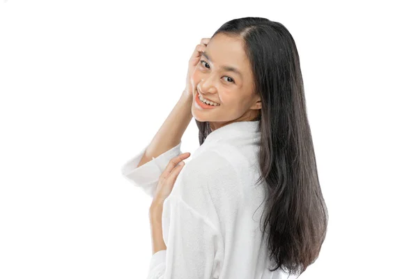 Beautiful woman with long hair standing sideways looking over her shoulder at the camera with smile — Fotografia de Stock