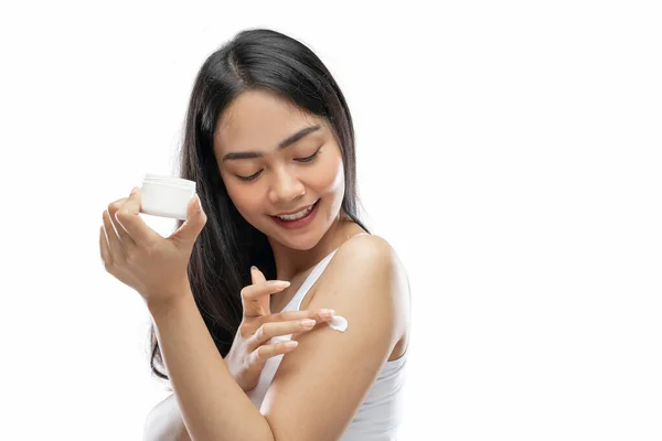 Asian woman wearing white underdress using body cream rub into arm — Stockfoto