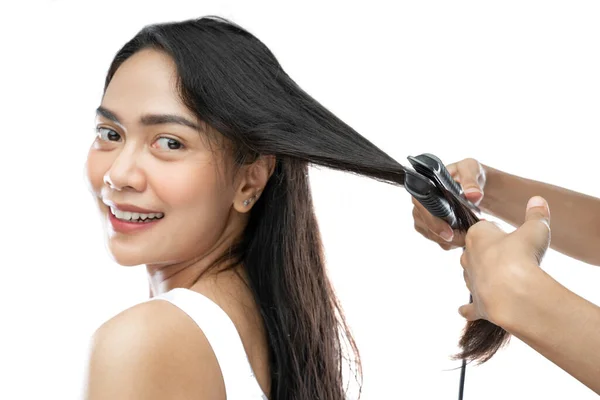 Hands of makeup artist using a hair straightener of young woman with long hair —  Fotos de Stock