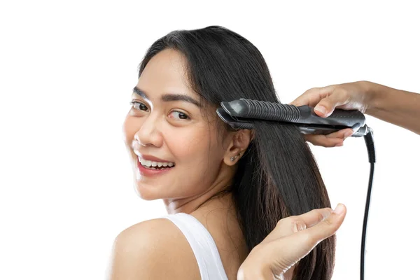 Smiling beautiful girl using a hair straightener — Stok fotoğraf