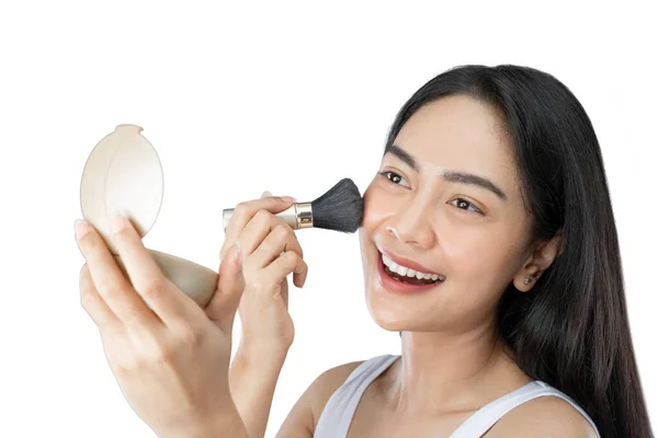 Beautiful young woman with long hair applying makeup using brush — Stockfoto