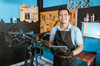 Portrait of smiling a repairman in an apron as work clothes using a pad