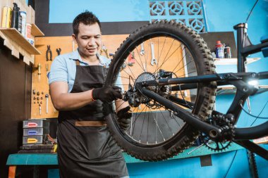 bicycle mechanic in aprons tightens spokes while fixing problems