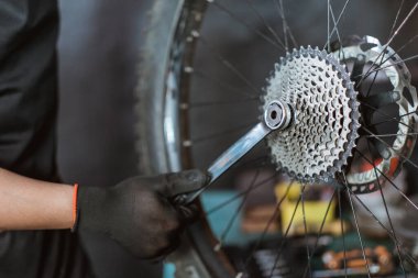 close up of a mechanics hand in gloves installing a sprocket using a wrench