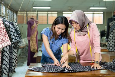 Seamstresses and supervisors measure the fabric with a ruler before sewing it