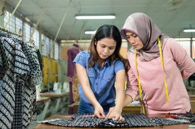 Asian seamstresses and work supervisors measure fabrics with a ruler according to the rules