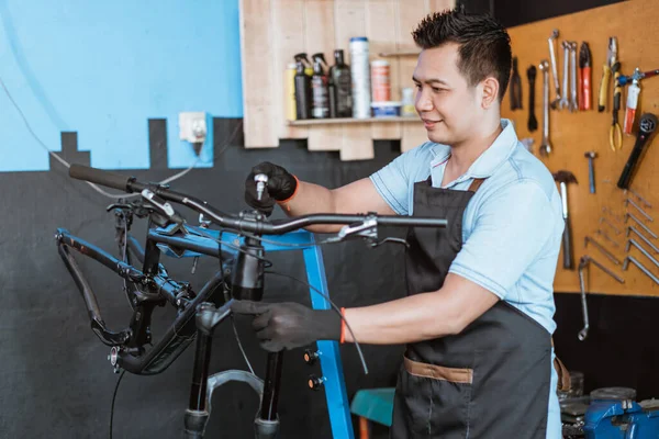 A young mechanic wearing gloves uses a shock wrench to remove the handlebar — Stock fotografie