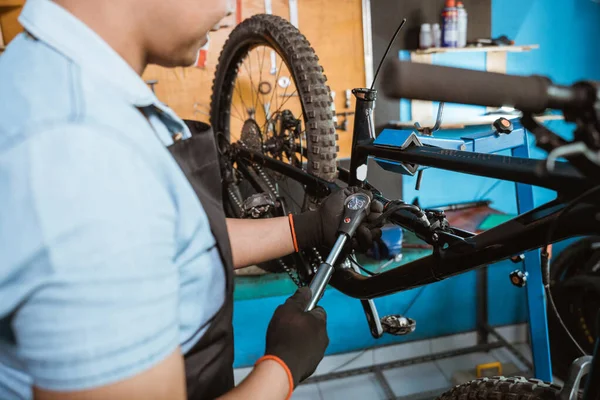 Mechanical hand in gloves using a bicycle pump with pressure gauge to adjust the rear suspension — Fotografia de Stock