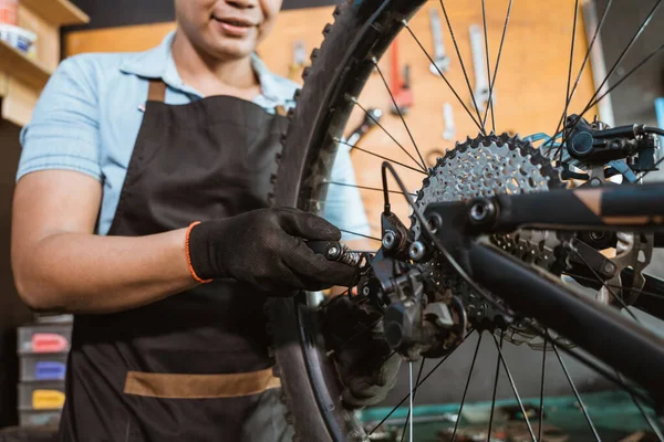 Hand of a mechanic wearing gloves setting bicycle spoke — Fotografia de Stock