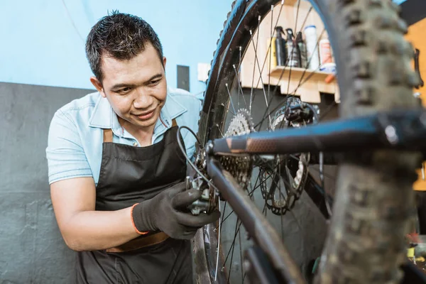 Bicycle mechanic in apron checks the rear mech while fixing problems — Fotografia de Stock