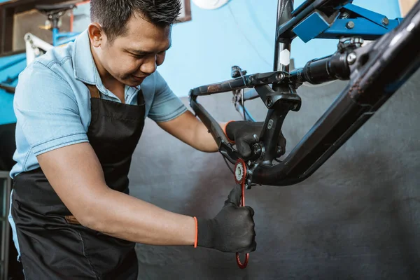 A bicycle mechanic uses a manual tool when assembling a bicycle frame — Fotografia de Stock