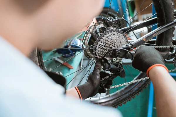 Bicycle mechanics hand with gloves uses an allen key to install the rear derailleur — Fotografia de Stock