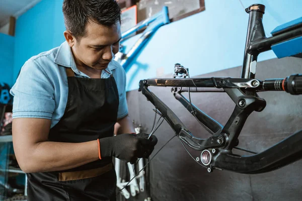 A bicycle mechanic attaches brake cables while assembling a bicycle frame —  Fotos de Stock