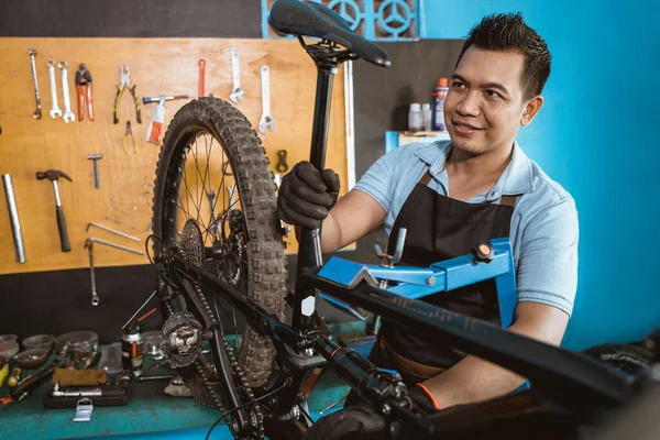 Bicycle mechanic in apron wears gloves when attaching bicycle saddle mount —  Fotos de Stock