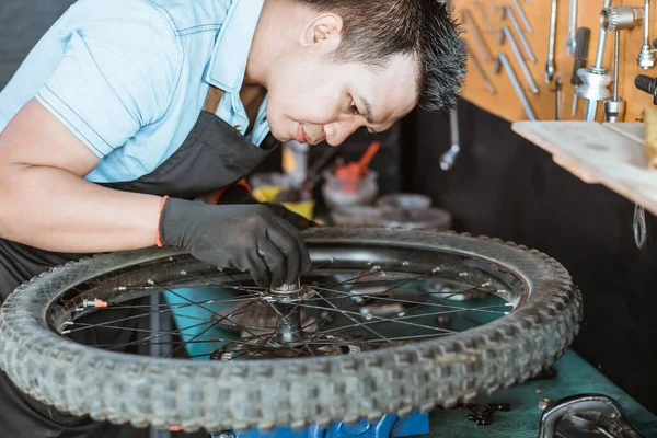 A mechanic wearing an apron and gloves installs a spacer on the hub shell — Φωτογραφία Αρχείου