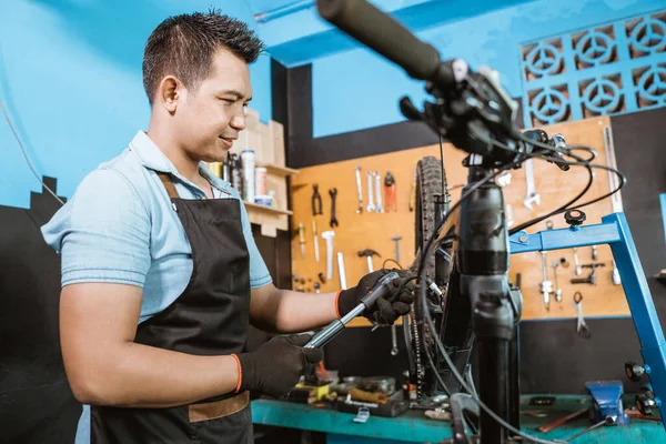 Mecánico de bicicleta guapo usando una bomba de bicicleta de alta presión para ajustar los amortiguadores —  Fotos de Stock