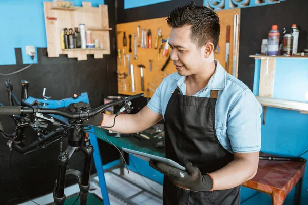 Retrato de un reparador en un delantal como ropa de trabajo usando una tableta para reparar —  Fotos de Stock