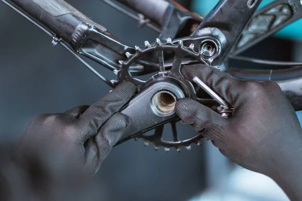 Close up of a mechanics hand wearing gloves installing the right crank arm on the bottom bracket — Fotografia de Stock