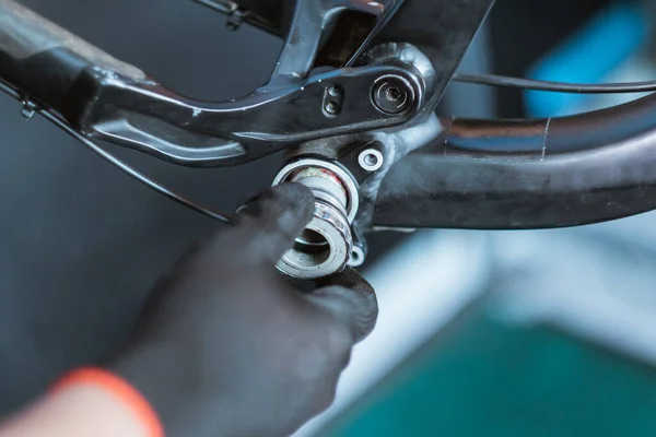 Close up of a mechanics hand wearing gloves holding the bottom bracket — Fotografia de Stock