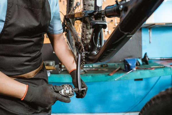A mechanics hands wearing gloves installing bicycle pedals with allen key — Fotografia de Stock