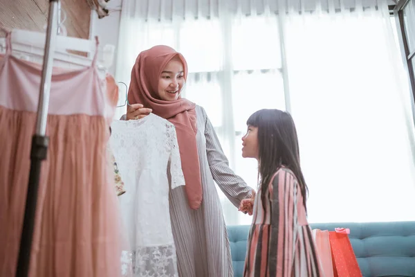 Madre musulmana elegir un vestido para su hija en la tienda de ropa —  Fotos de Stock