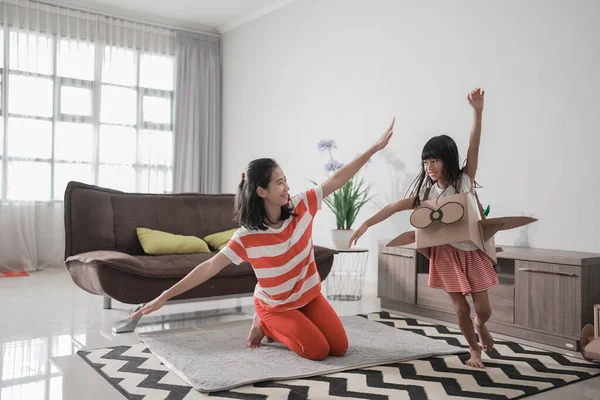 Chica jugando con cartón juguete avión en casa con madre — Foto de Stock