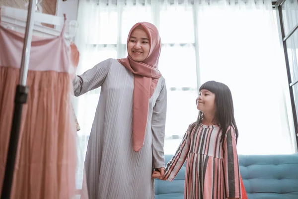 Madre musulmana elegir un vestido para su hija en la tienda de ropa — Foto de Stock