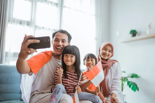 Indonesian muslim asian family making selfie and video call using their phone at home — Stock fotografie