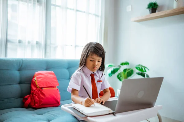 first grade school student with uniform during online class study with teacher at home