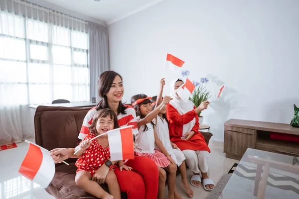 Ibu dan anak merayakan kemerdekaan indonesia hari di rumah mengenakan merah dan putih dengan bendera indonesia — Stok Foto