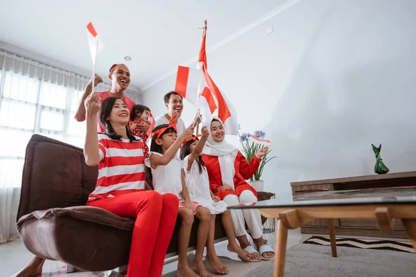 Upphetsad indonesisk familj supporter medan du tittar på sport match på TV hemma — Stockfoto