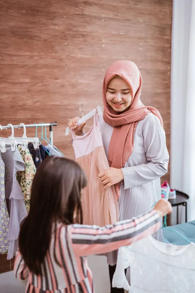 Мать-мусульманин выбирает платье для дочери в магазине одежды — стоковое фото
